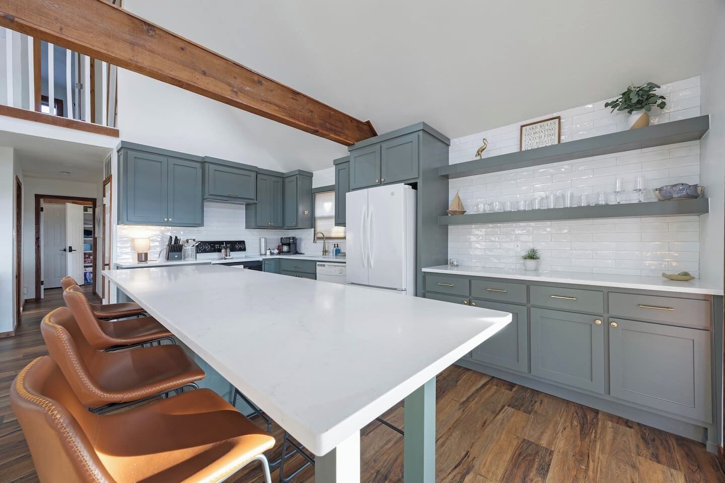 A modern kitchen with grey cabinets, a white island, and wooden flooring.