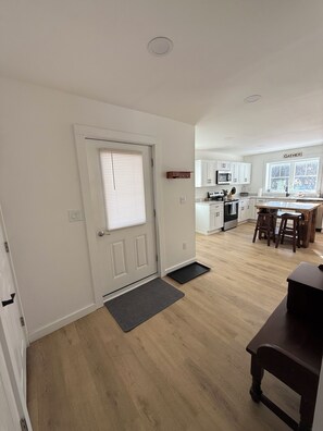 Une cuisine moderne avec des meubles blancs, un îlot central et un coin repas doté de chaises en bois.