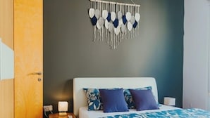 A bedroom with a bed, bedside table, and a wall-mounted decoration. - Cozy One-Bedroom Penthouse in Sliema (Tas-Sliema)