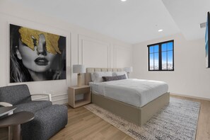 A modern bedroom with a large bed, bedside tables, a sofa, a large window, and a city view.