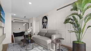 Ein modernes Wohnzimmer mit einem grauen Sofa, einem Couchtisch, einem Beistelltisch und einer großen Pflanze in einem Topf.