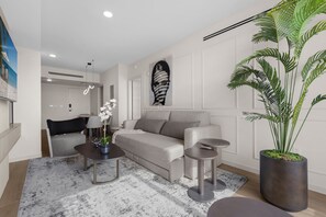 Un salon moderne avec un canapé, une table basse et une grande plante en pot.