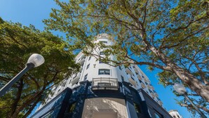 Ein mehrstöckiges Gebäude mit einem zentralen Turm, großen Fenstern und einem Balkon.