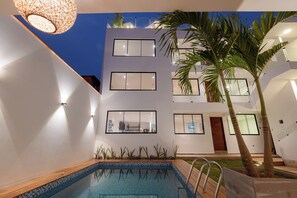 Ein modernes Gebäude mit Pool, Holzterrasse und einer Palme.