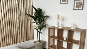 Een moderne woonkamer met een houten bank, een houten salontafel, een potplant, een houten boekenkast en een geweven vloerkleed.