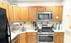 A kitchen with wooden cabinets, a stainless steel microwave, a gas stove, and an oven.