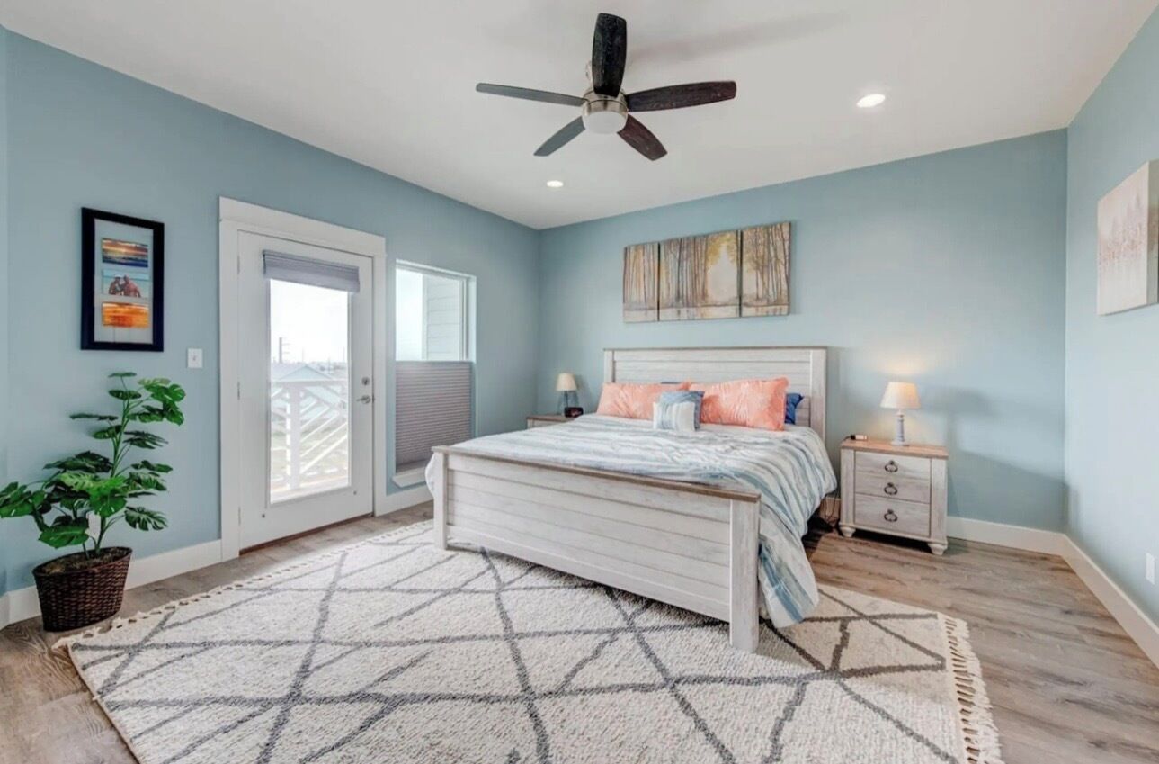 A bedroom with a bed, bedside tables, a ceiling fan, and a view through a door.