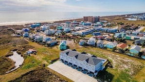 En kystby med en blanding af boliger og erhvervsbygninger, en strand i baggrunden og en stor blå bygning i forgrunden.
