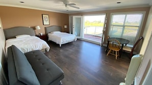 Una habitación de hotel con dos camas, un área de descanso y un balcón.