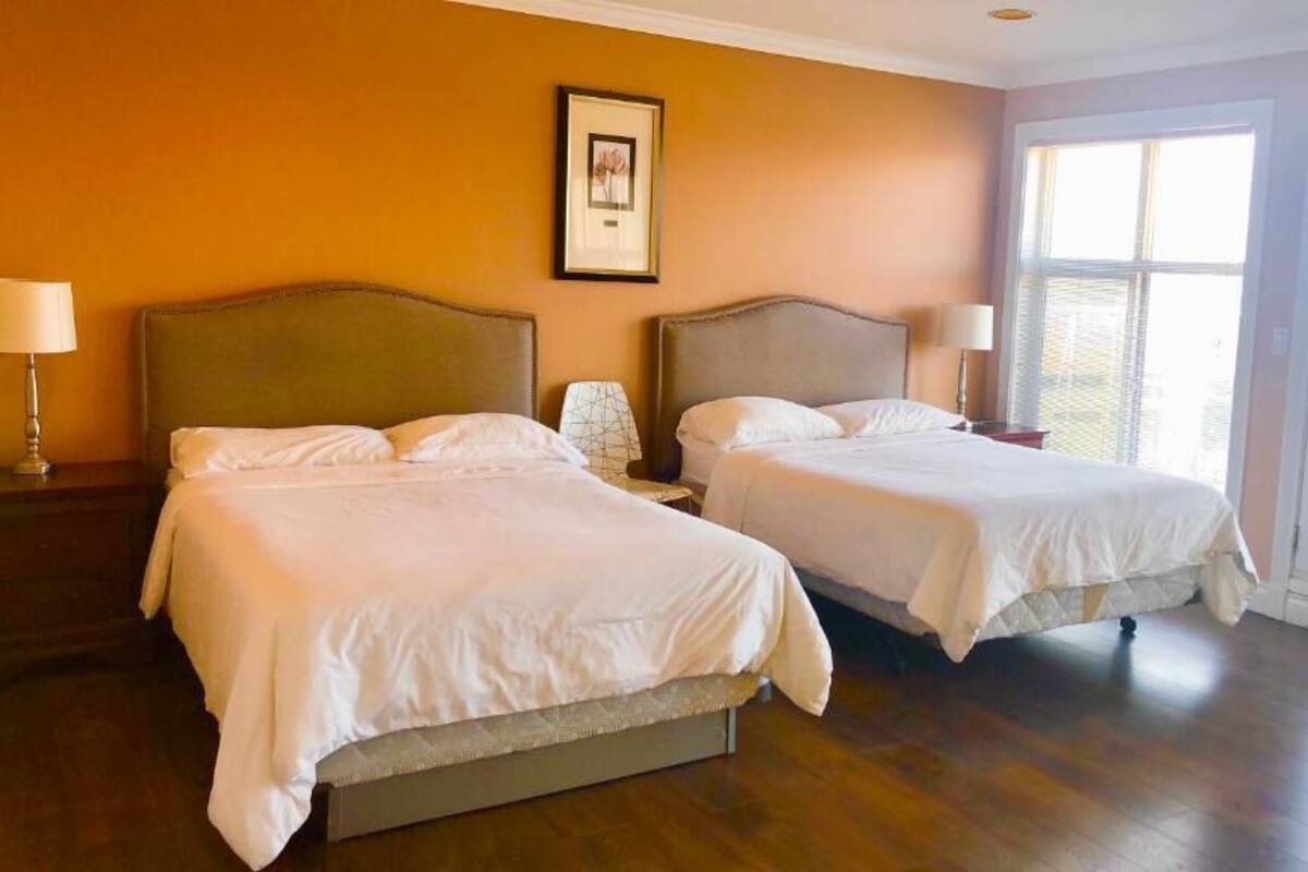 Una habitación de hotel con dos camas, un cuadro enmarcado en la pared y un ventanal grande.