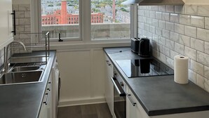 A modern kitchen with a window view, stainless steel appliances, and a black countertop. - 2-bed Apart in the Heart of Aberdeen (Aberdeen)
