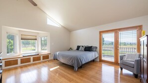 Une chambre à coucher avec un lit, un banc, une chaise et une vue sur l’extérieur.