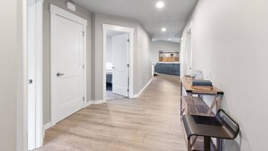 A hallway with wooden flooring, white walls, and a dining area with a table and chairs. - Near Perry, Near Perfect (Spokane)