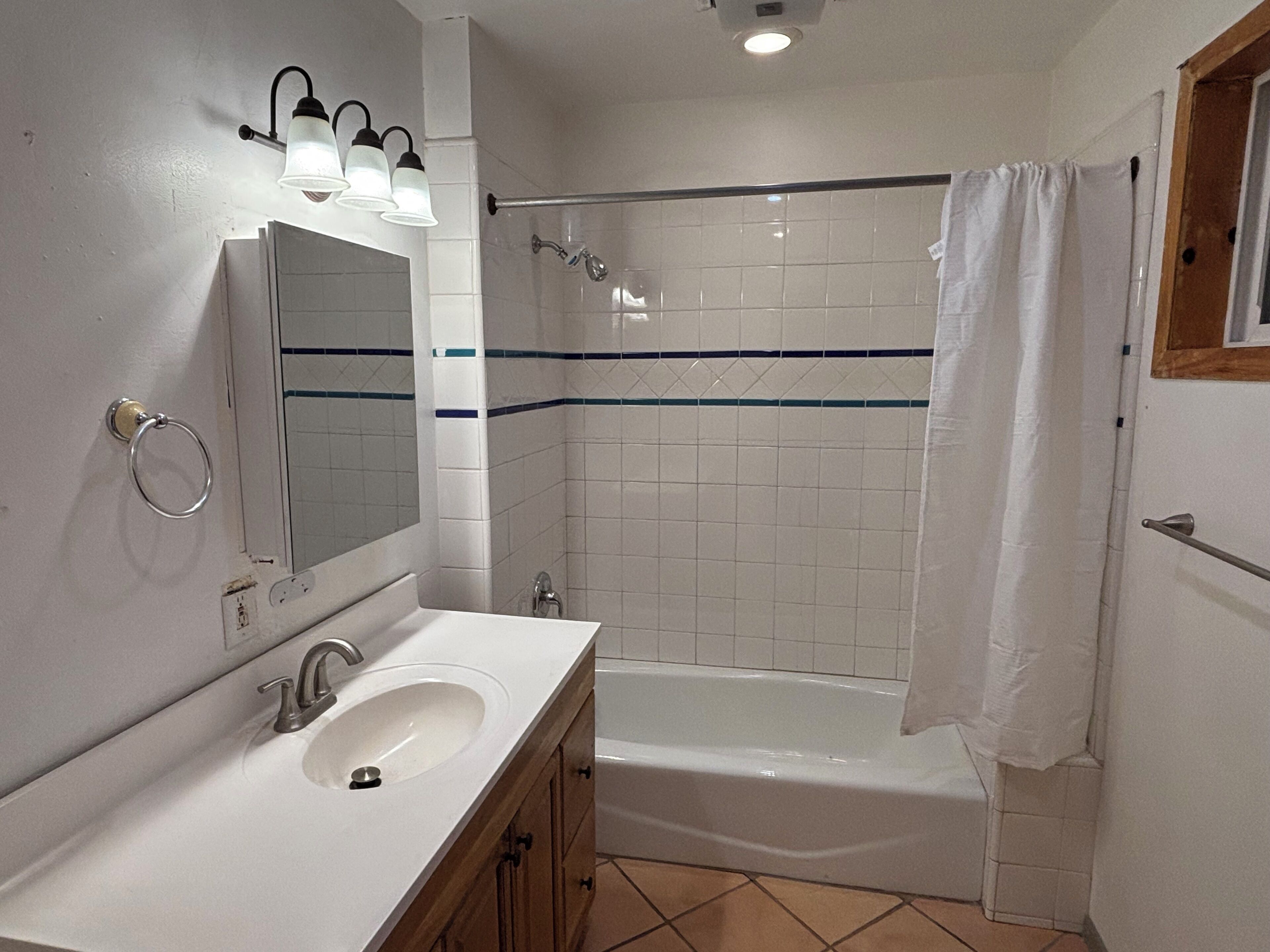 A bathroom with a sink, mirror, and shower.