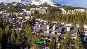 Un resort con diversi edifici, un parcheggio e una montagna innevata sullo sfondo.