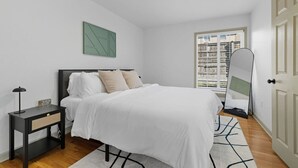 Une chambre à coucher moderne avec un lit, une table de chevet et un grand miroir.