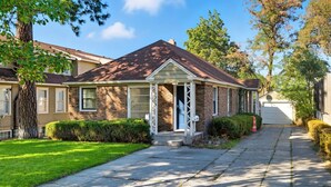 Une maison de plain-pied en briques, dotée d’un porche à l’avant, d’un garage et d’une pelouse bien entretenue.