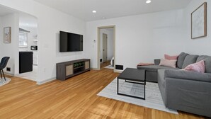 Un salon moderne avec un canapé gris, un téléviseur à écran plat et un plancher en bois.