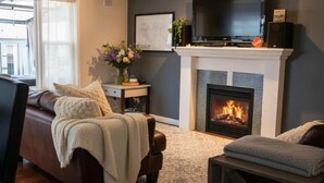 Ein Wohnzimmer mit Kamin, einer Couch, einem Fernseher und einem Couchtisch.