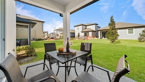 Un patio coperto con tavolo e sedie, una bottiglia di vino e un cestino di pane.