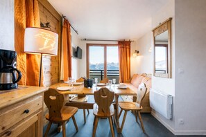Ein gemütlicher Essbereich mit Holzmöbeln, einer Kaffeemaschine und Bergblick durch das Fenster.