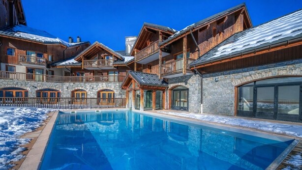 Ein Resort mit Schwimmbad, Steinmauern und Holzbalkonen.