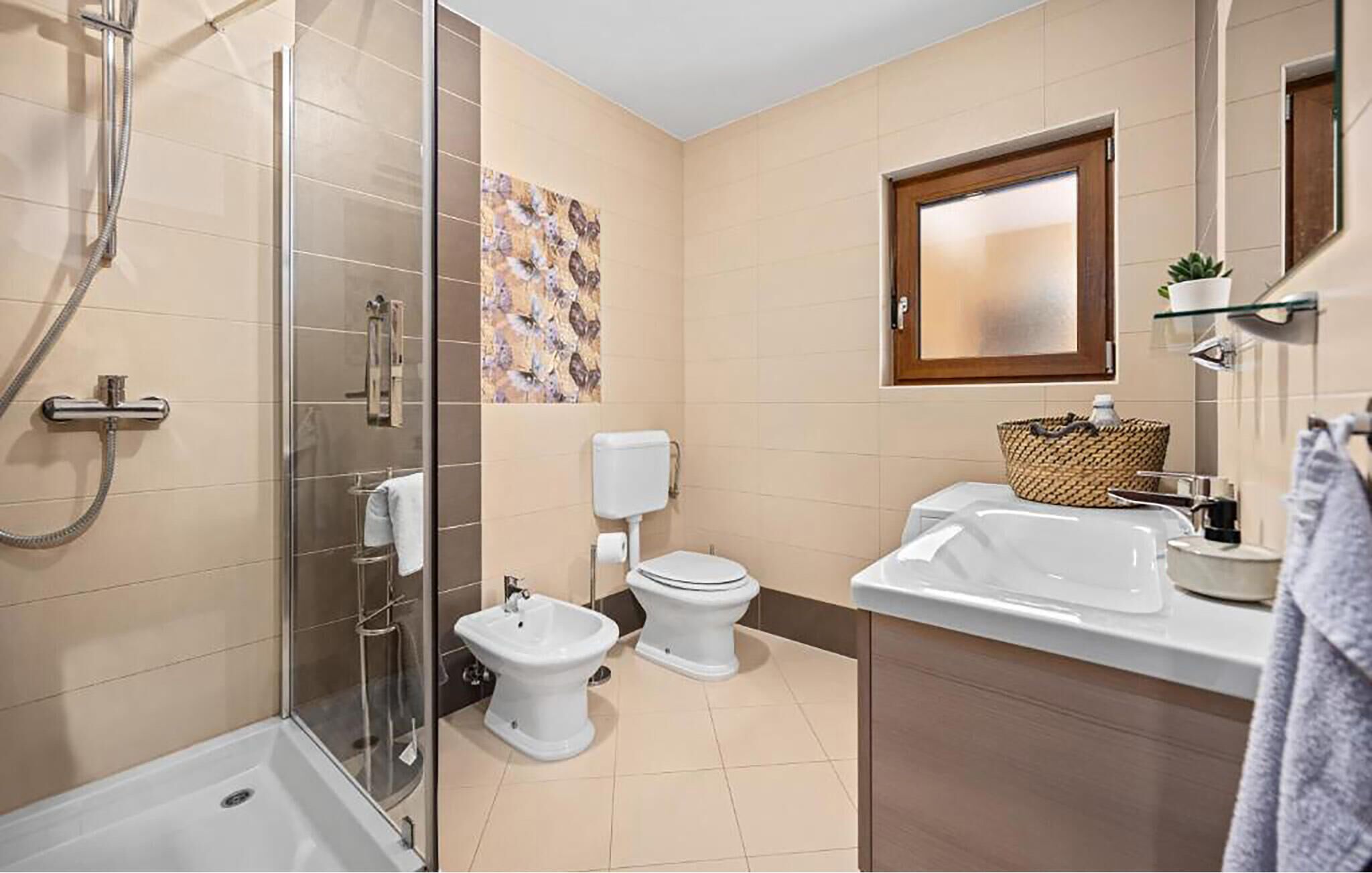 Een moderne badkamer met douche, toilet, bidet en wastafel.