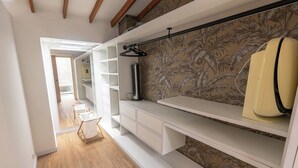 A walk-in closet with white cabinetry, a hanging rod, and a patterned wallpaper. - Duplex en el Primer Parque de laureles (Medellín)