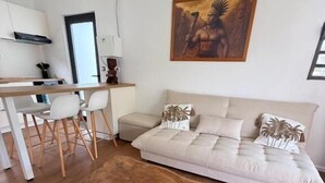 A modern living room with a large wooden coffee table, a sofa, and a dining area with chairs.