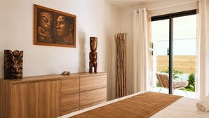 A bedroom with a wooden dresser, a framed artwork, a curtain, and a view of the outside.