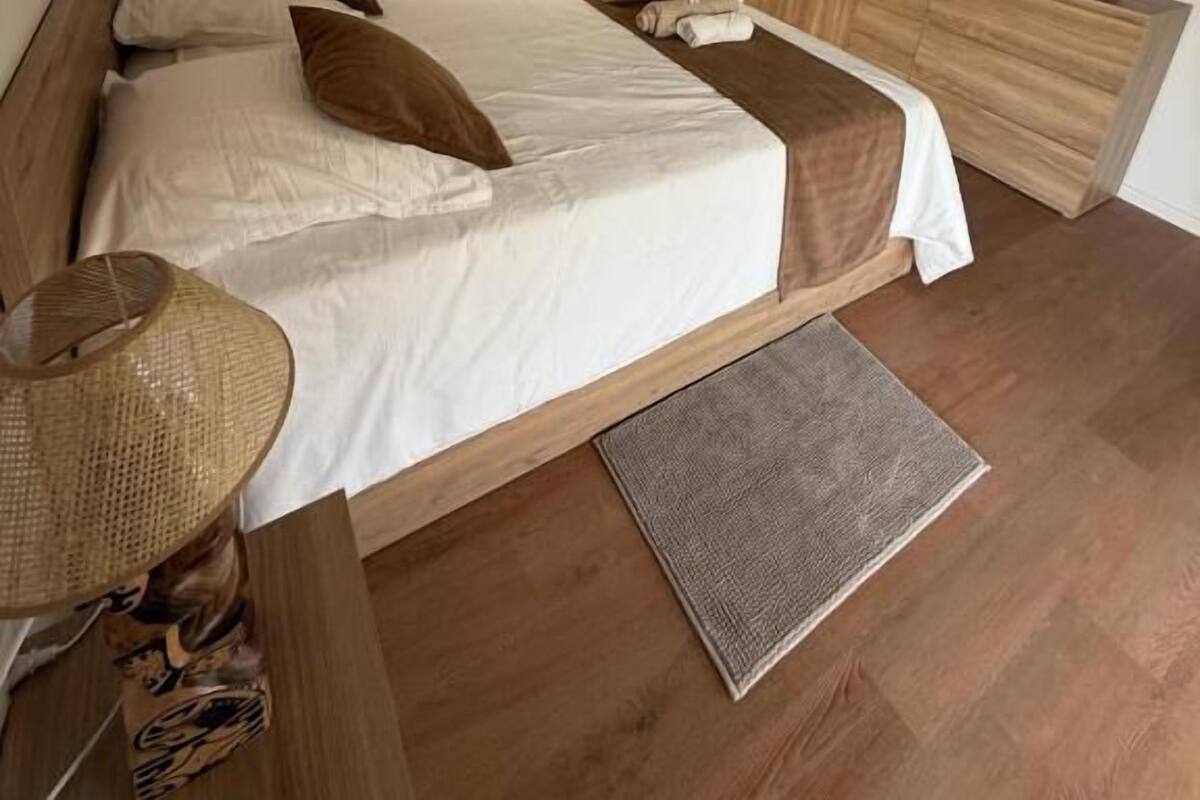 A bedroom with a bed, bedside table, lamp, and a ceiling fan.