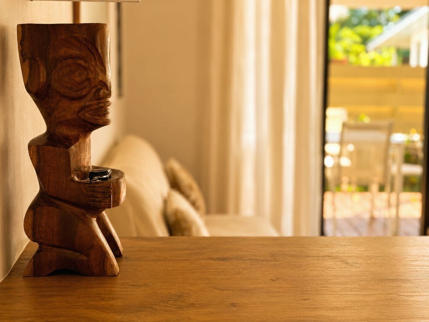 A wooden sculpture on a table in a room with a view of an outdoor area.