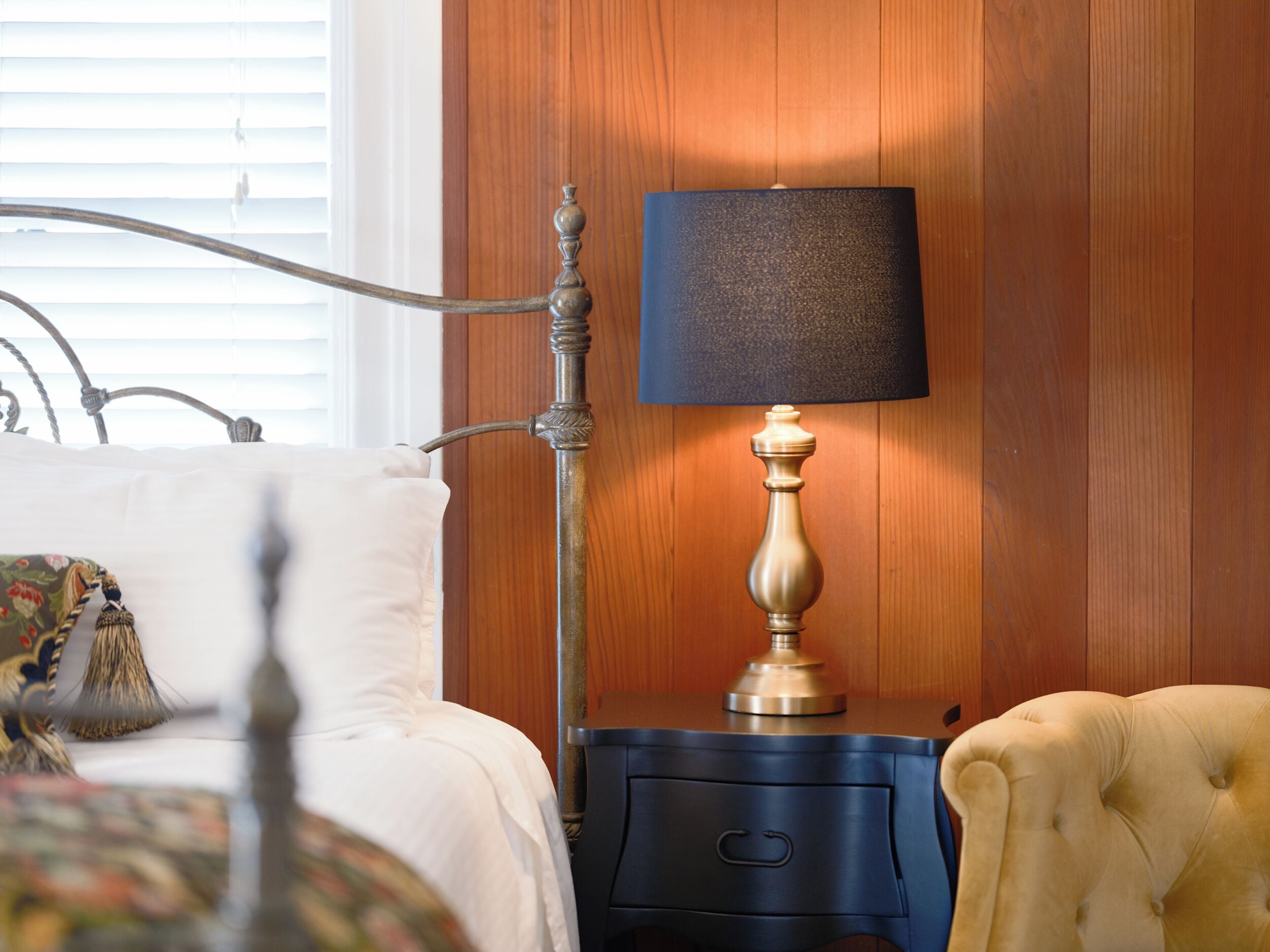 A bed with a floral pillow, a bedside table with a lamp, and a nightstand with a drawer.