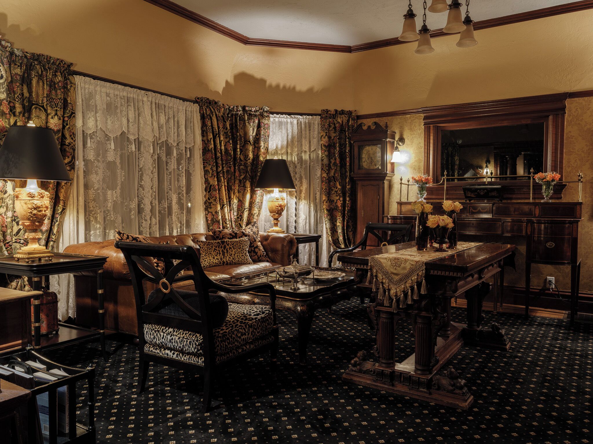 Une pièce au décor traditionnel, avec un canapé en cuir, des rideaux à motifs et des meubles classiques.