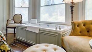 Un baño con bañera, una silla, un sofá y una lámpara.