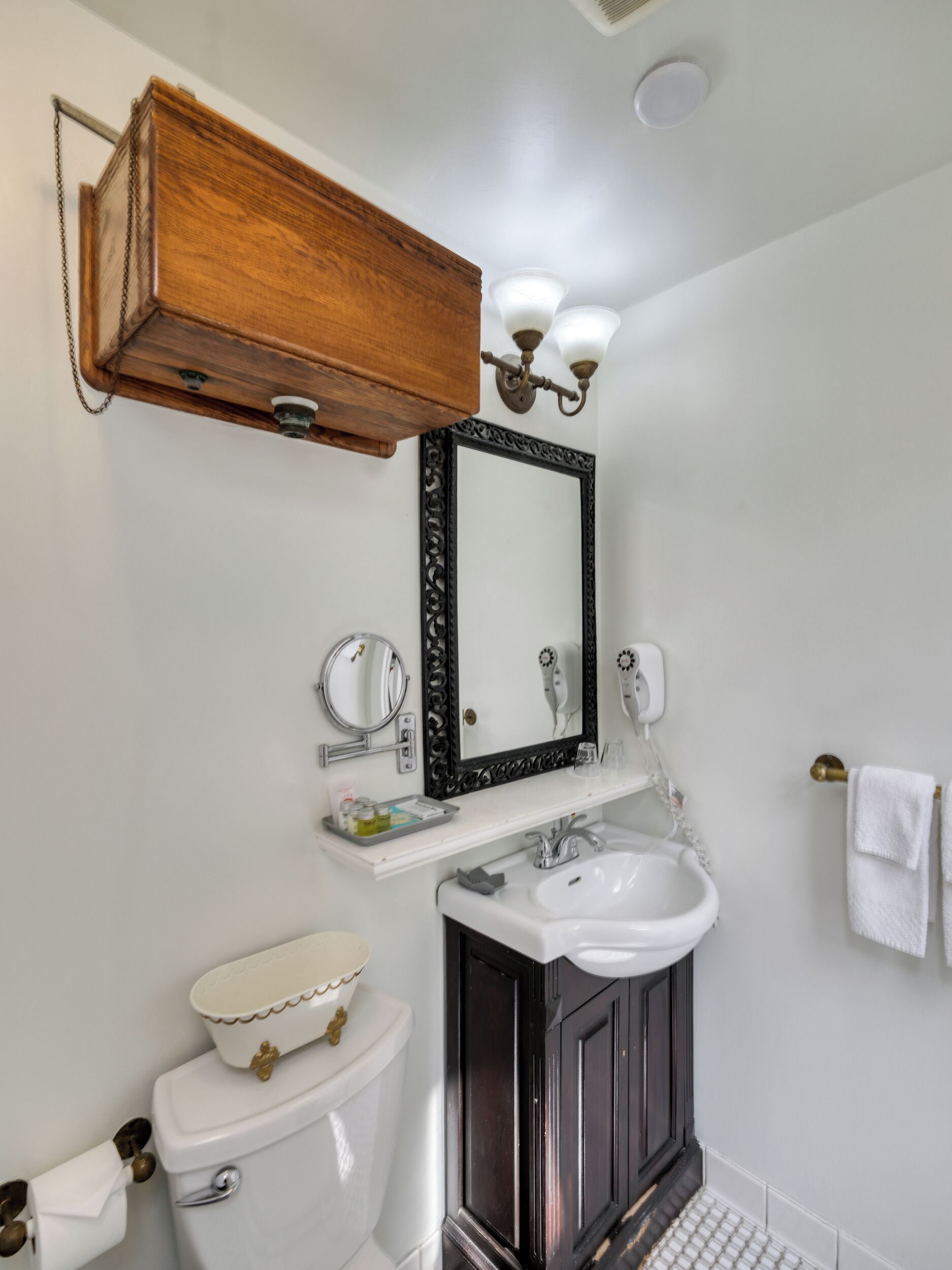 A bathroom with a white toilet, a white sink, a black vanity, and a wooden cabinet above the sink.