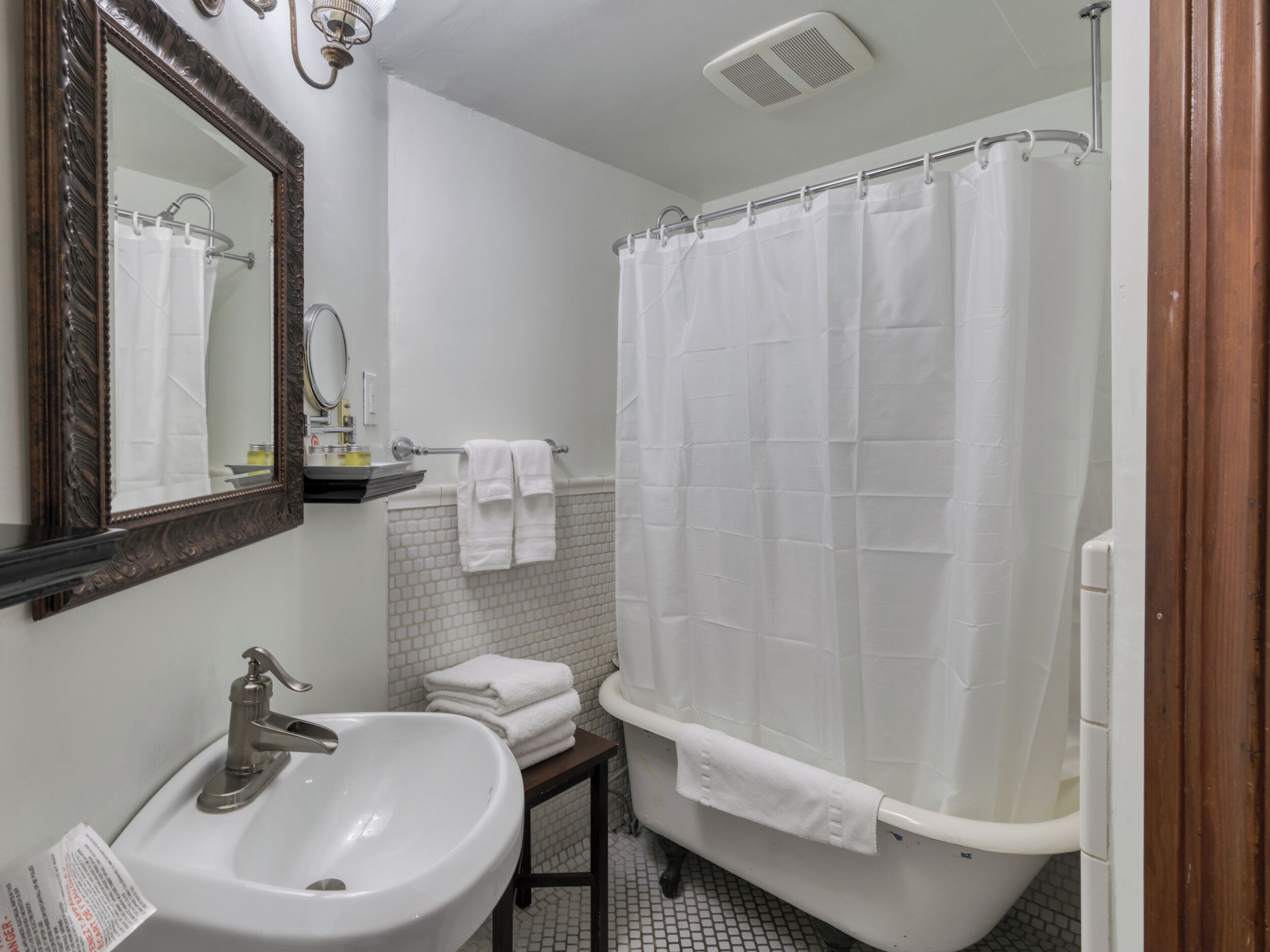 A bathroom with a white sink, mirror, and bathtub. There are towels on the sink and a shower curtain.