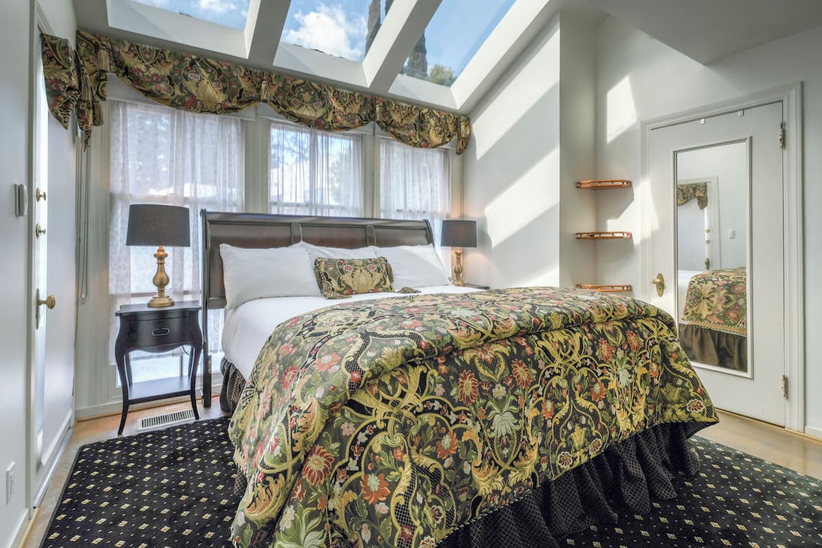 Une chambre à coucher avec un grand lit, une table de chevet, un miroir et une lucarne.