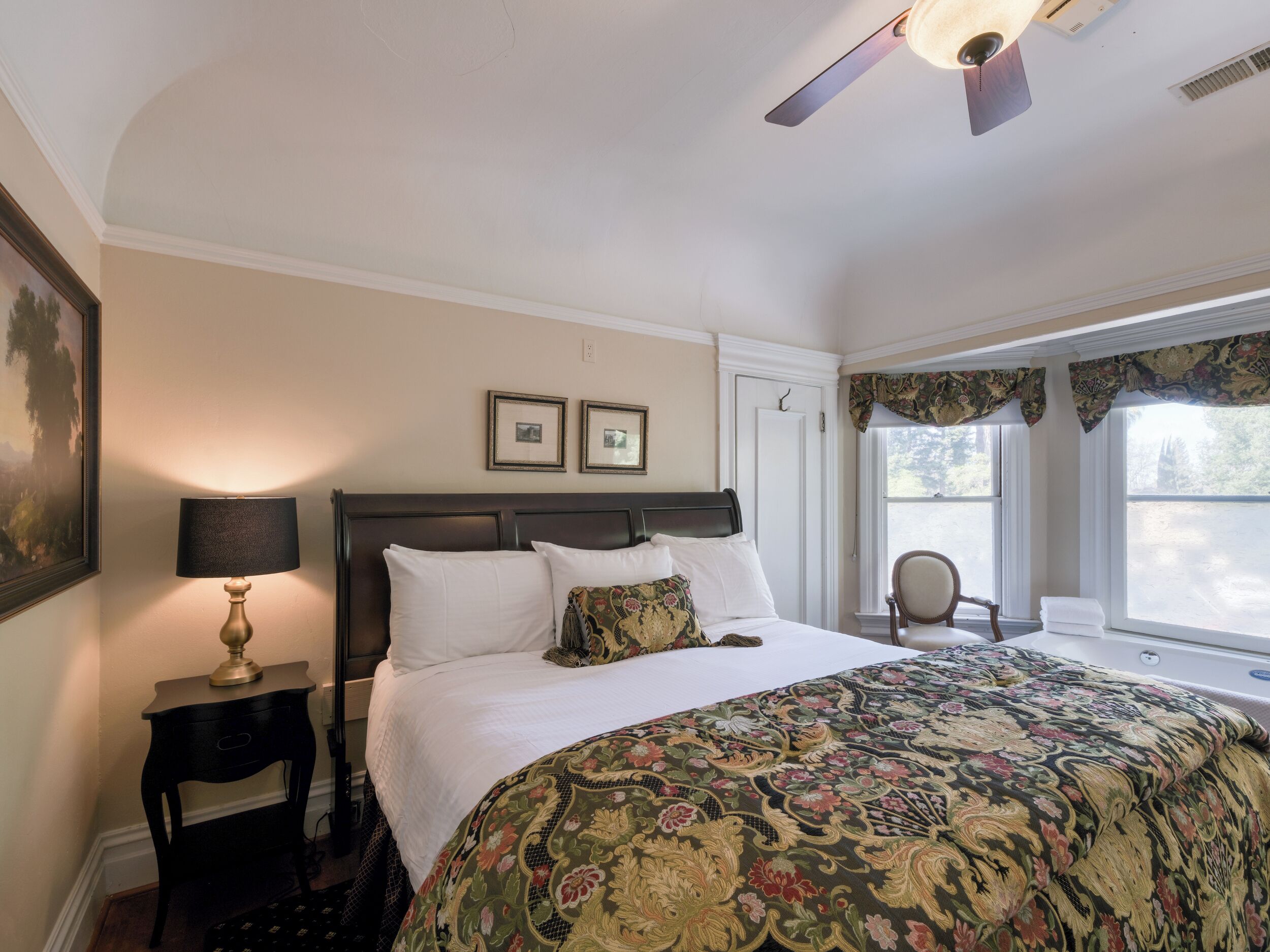 A neatly arranged bedroom with a bed, a nightstand, a chair, and a window with curtains.