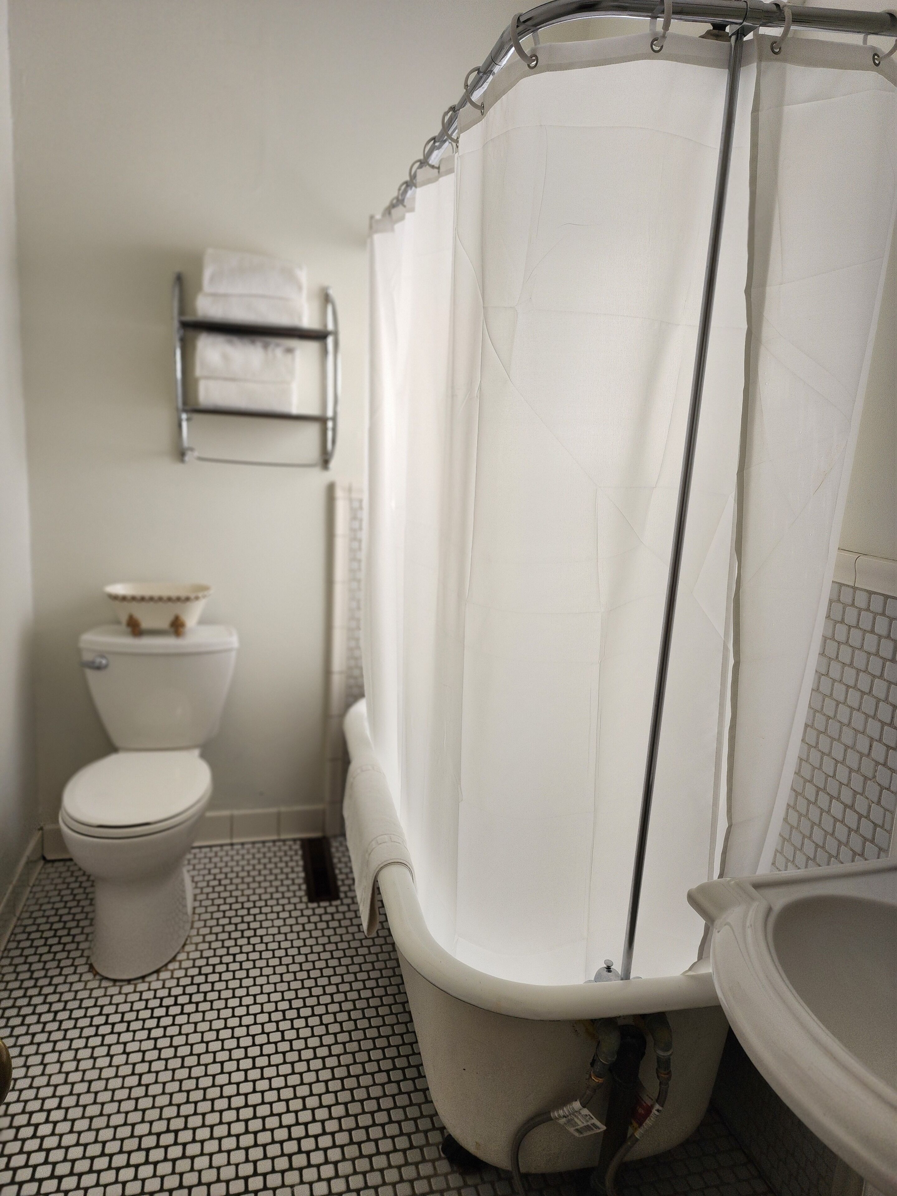 A bathroom with a toilet, a bathtub with a shower curtain, and a sink.