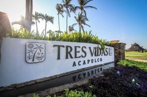 A sign for Tres Vidas Acapulco with palm trees and a clear sky in the background. - Oceanfront luxury apartment
beach access (Acapulco)