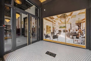 Un intérieur moderne avec une grande porte vitrée donnant sur un espace repas, un sol carrelé et un lustre.