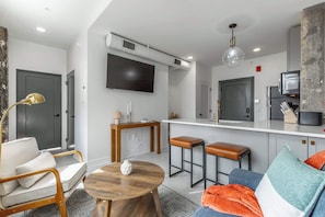 A modern living room with a sofa, a coffee table, and a TV mounted on the wall.