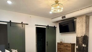 Een moderne slaapkamer met een bed, een aan de muur bevestigde televisie en een schuifdeurkast.