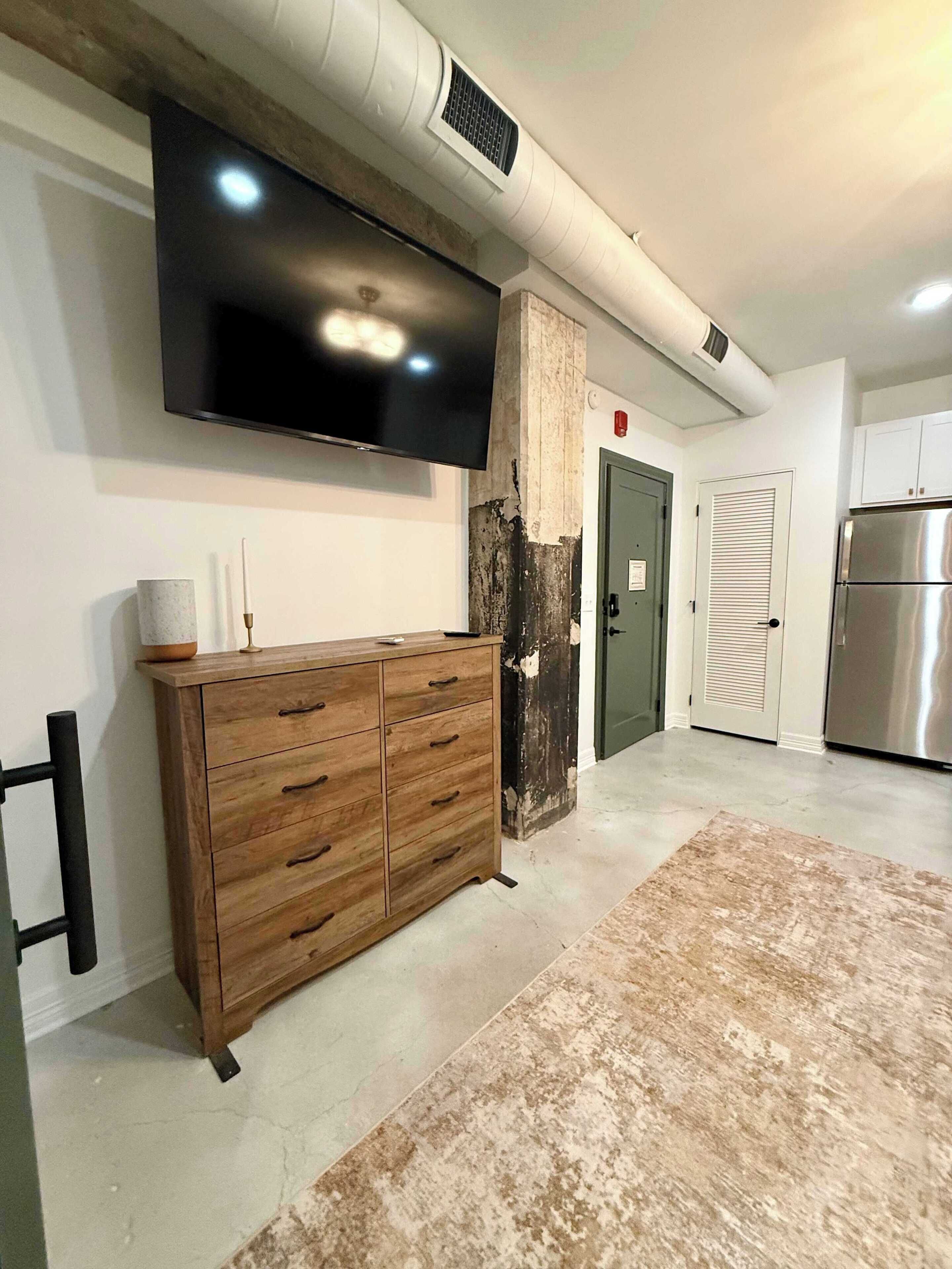 Una cocina moderna con televisión integrada, un mueble de madera y un refrigerador de acero inoxidable.