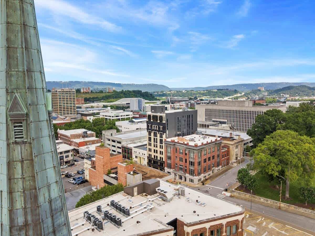 A cityscape with various buildings, including a tall structure on the left and a mix of modern and older architecture.