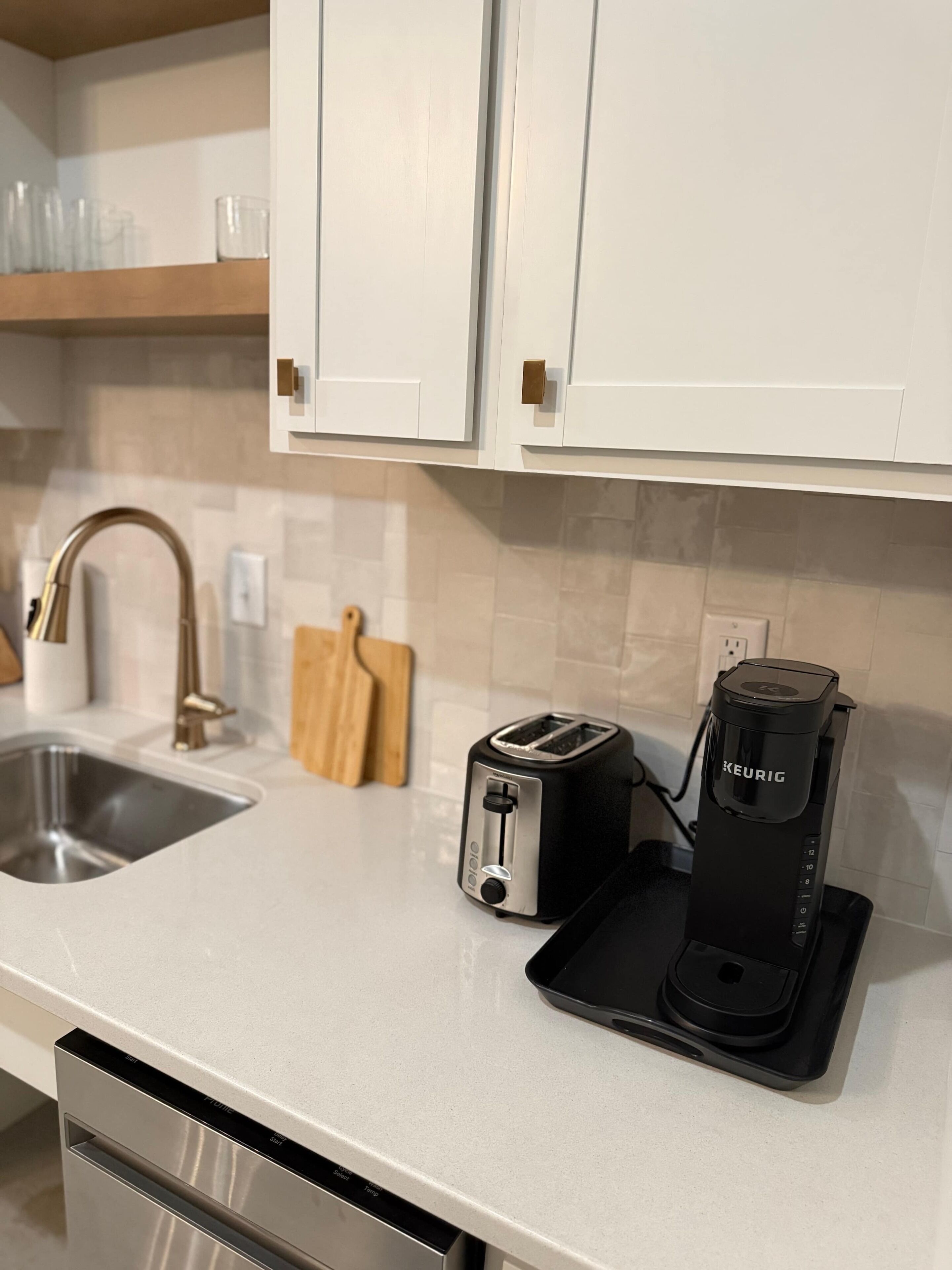 A modern kitchen with a stainless steel sink, a toaster, and a Keurig coffee maker on the counter.