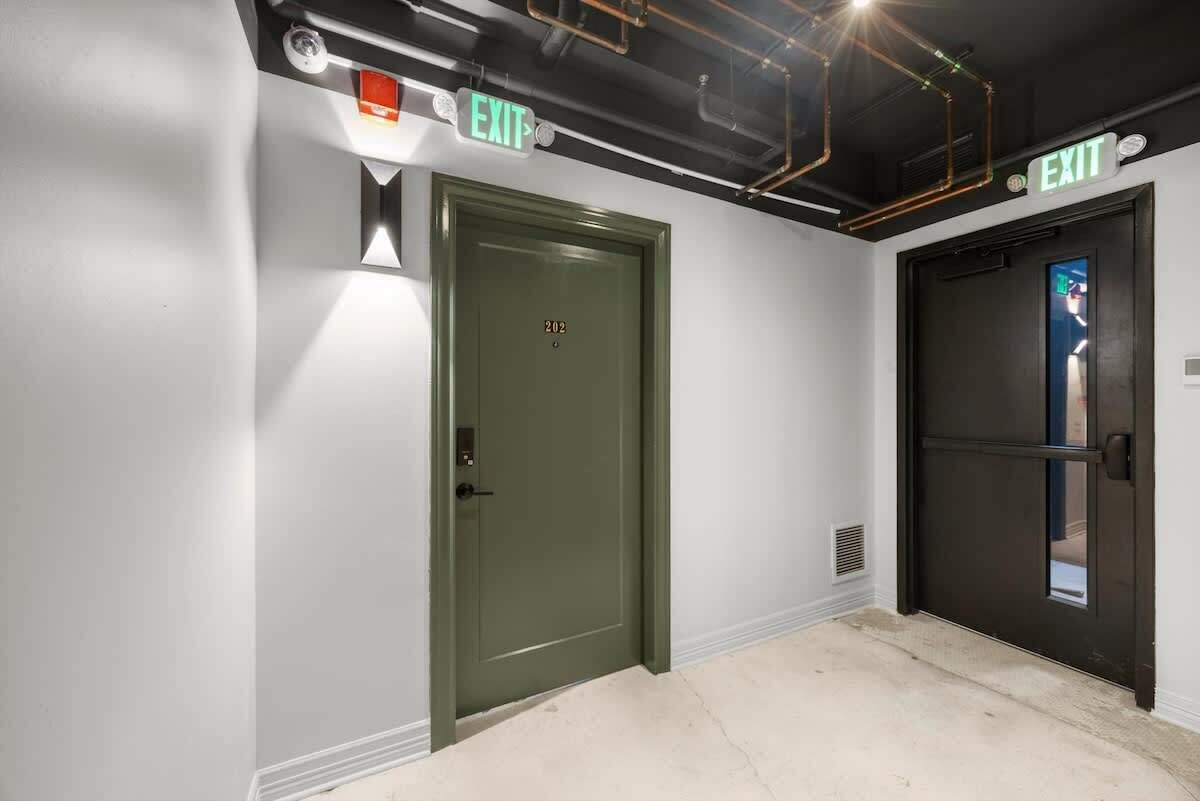A hallway with two doors, one green and one black, both marked with 'EXIT' signs.