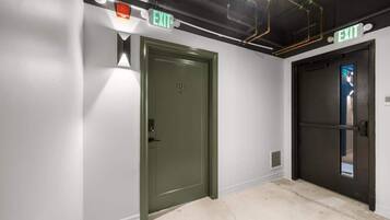 A hallway with two doors, one green and one black, both marked with 'EXIT' signs.