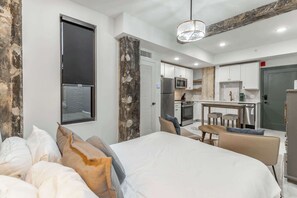 Une chambre d’hôtel moderne dotée d’un grand lit, d’un coin repas et d’une kitchenette.